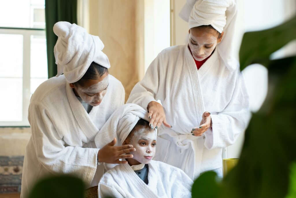 Mother and daughters enjoy a spa day at home with facial treatments and relaxation.